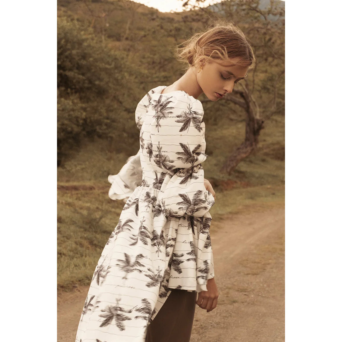 a model far from the cities showing us what to wear with a flower dress in white and a sepia tone