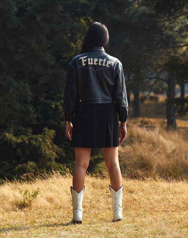 a model styling a black leather jacket with the word "fuerte" in its bag in an OnPost Style