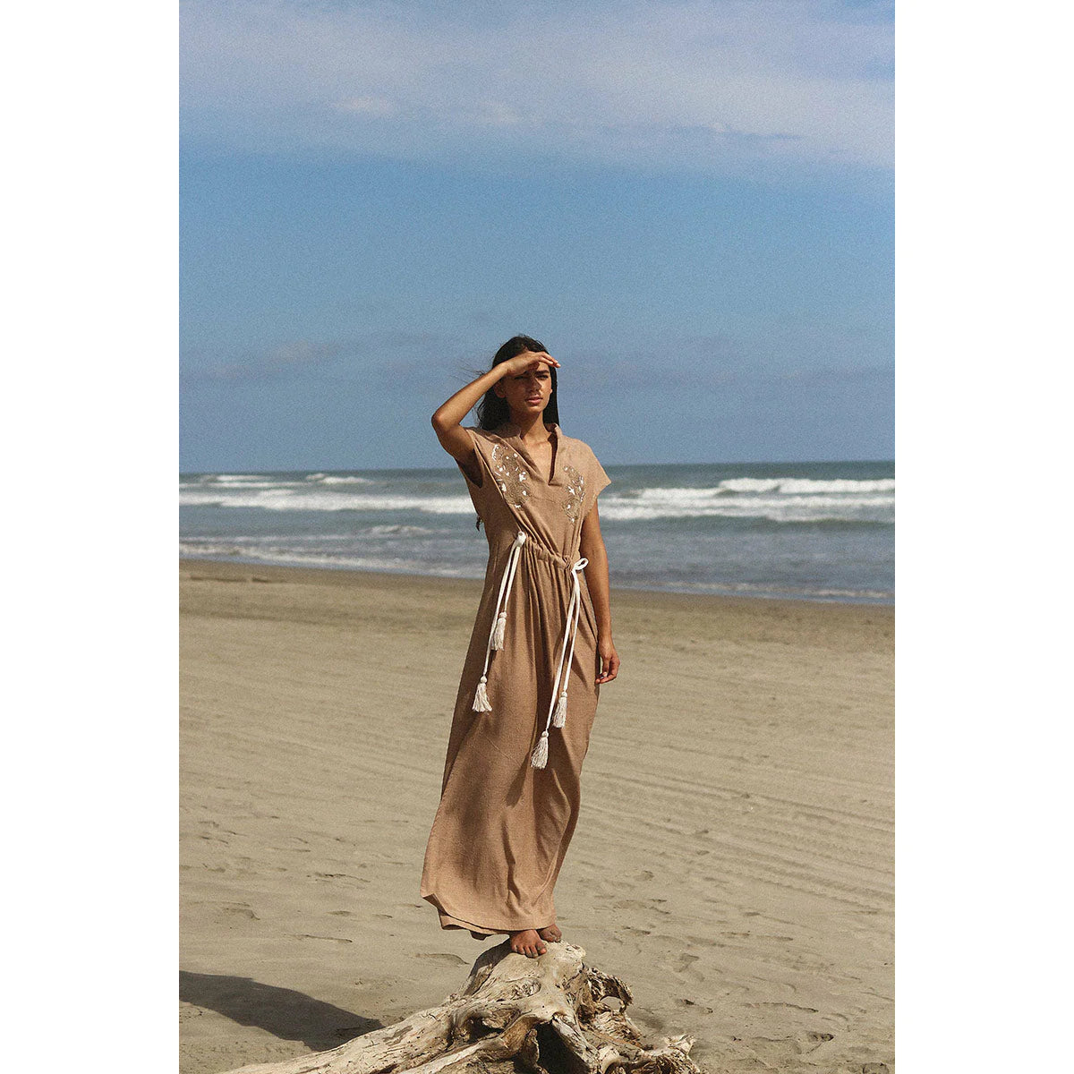 a model on a beach showing us how to style a maxi dress that is brown with OnPost