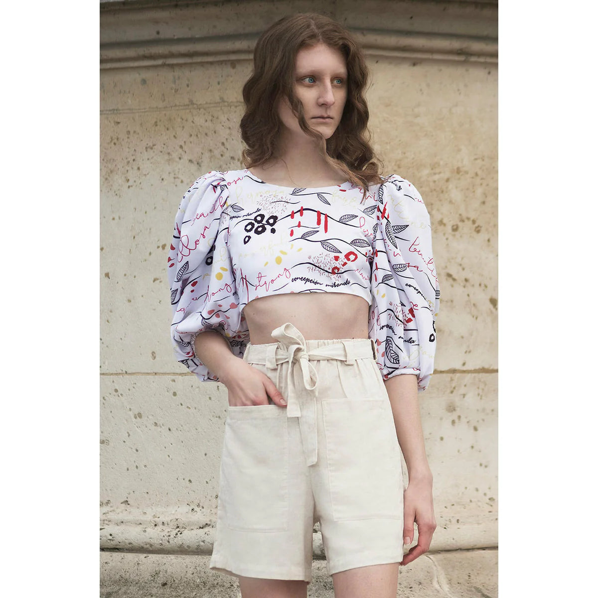 a model with curl with a puff blouse and wearing a line short for spring season